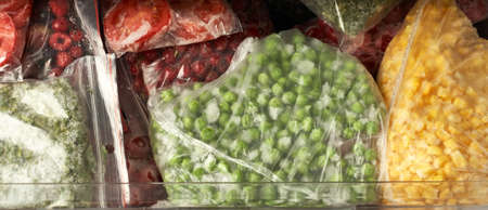 A set of frozen foods for the winter. Frozen berries, vegetables, corn, green peas, tomatoes in the...