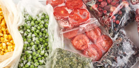 A set of frozen foods for the winter. Frozen berries, vegetables, corn, green peas, tomatoes in the...