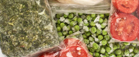 Set of frozen food packed in bags. Store vegetables for the winter, top view. Tomato, green peas, greens.の写真素材