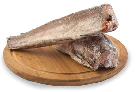 Frozen hake fish lies on the board, isolated on white background. Side view.