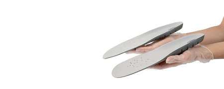 Orthopedist holds the insoles in his hands on white background, close-up. Only hands, on hygienic...