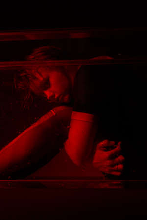 Horrible portrait of a young girl in a horror room with a red light.
