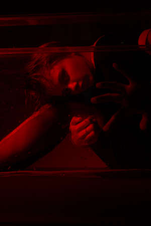 Horrible portrait of a young girl in a horror room with a red light.の写真素材