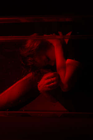 Horrible portrait of a young girl in a horror room with a red light.の写真素材