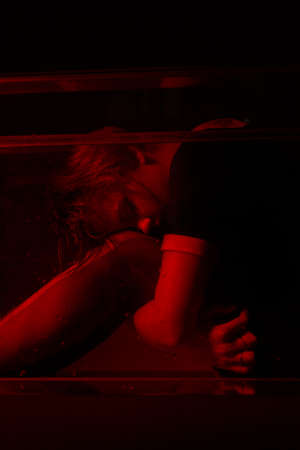 Horrible portrait of a young girl in a horror room with a red light.の写真素材