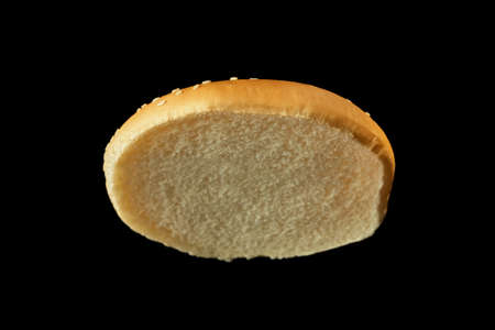 Slice of burger bun isolated on black background.の写真素材