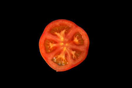 Tomato slice cut round shape isolated on black background.の写真素材