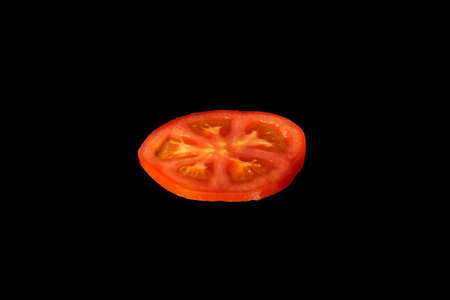 Tomato slice cut round shape isolated on black background.の写真素材