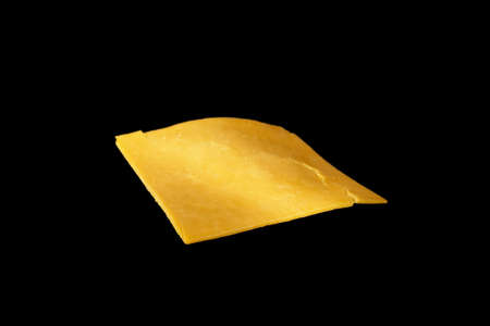 Slice of cheddar cheese isolated on black background flying prepared ingredient.の写真素材