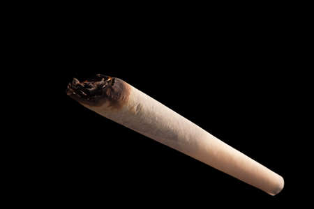 Hand-rolled jamb with marijuana close-up macro isolated on black background.