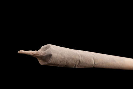 Hand-rolled jamb with marijuana close-up macro isolated on black background.