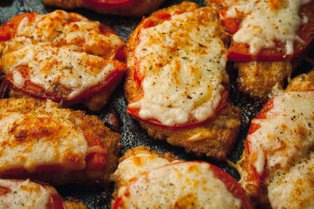 Baked chicken fillet with cheese and tomato on a baking tray for roasting. Meat dish for the festive table.の写真素材