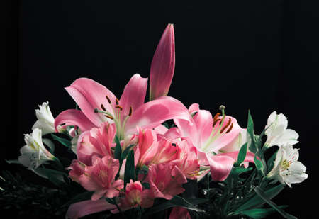 Lily bouquet close-up on a black background. Composition from flowers and twigs of leaves.の写真素材