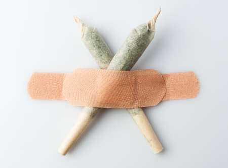 Cannabis jamb is glued with sticky plaster on a white wall.の写真素材