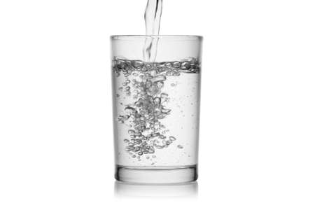 Splash jet of water pours in glass with bubbles isolated on a white background without glare. Reflection on the surface. Back light.の写真素材