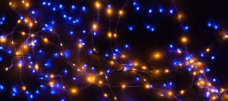 Christmas, festive background with glowing garland. Colorful lights on a dark background. New Year cards, postcard, banner. With space for text. Soft focus.の写真素材