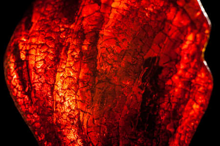 Macro close-up of rough raw amber stone isolated on black background.の写真素材