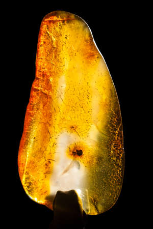 Macro close-up of rough raw amber stone isolated on black background.の写真素材