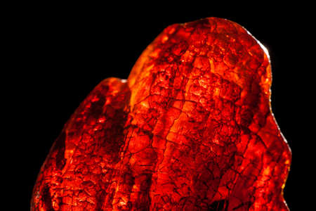 Macro close-up of rough raw amber stone isolated on black background.の写真素材