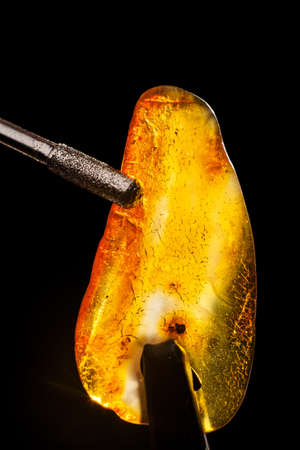 Amber stone processing macro close-up. Stone jewelry, polishing process. Sunstone and drill.の写真素材