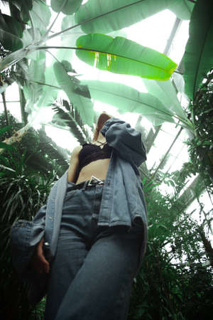Beautiful young blonde girl portrait outdoors in a botanical garden among exotic plants.の写真素材