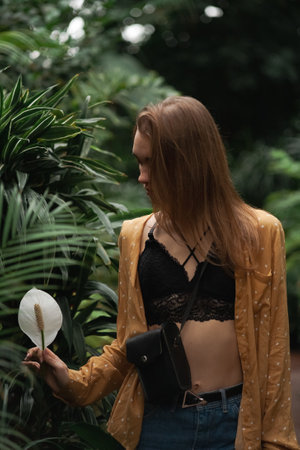 Beautiful young blonde girl portrait outdoors in a botanical garden among exotic plants.