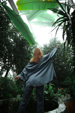 Beautiful young blonde girl portrait outdoors in a botanical garden among exotic plants.の写真素材