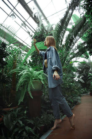 Beautiful young blonde girl portrait outdoors in a botanical garden among exotic plants.の写真素材