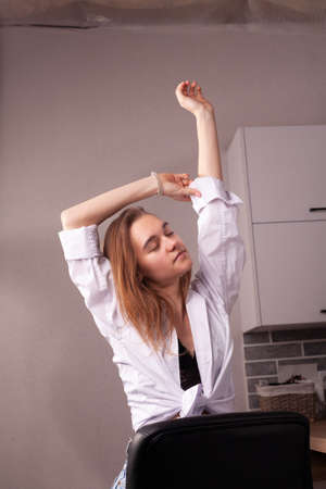 Portrait of a beautiful blonde girl in simple everyday things sitting indoors.の写真素材