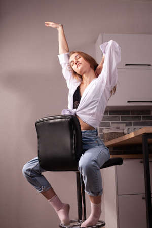 Portrait of a beautiful blonde girl in simple everyday things sitting indoors.の写真素材