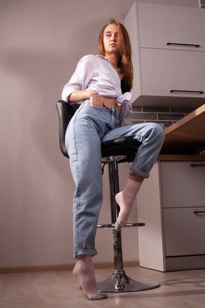 Portrait of a beautiful blonde girl in simple everyday things sitting indoors.の写真素材