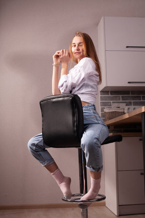 Portrait of a beautiful blonde girl in simple everyday things sitting indoors.の写真素材