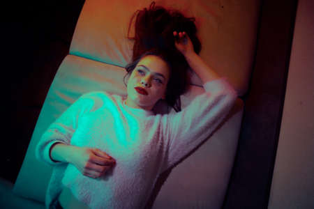 Portrait of a girl at home lies on the couch alone, going crazy.の写真素材