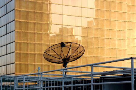 Satellite with sunset reflection on flat building backgroungの写真素材