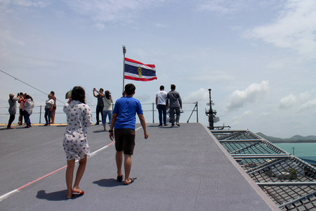 Chonburi, Thailand. 14 August 2016 - Tourist on deck of HTMS Chakri Naruebet (CVH-911) Royal Thai Naval base, Navy Aircraft Carrier at port of Sattahip, windy nation flag in sunshine and deep blue seaのeditorial素材