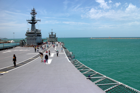 Chonburi, Thailand. 14 August 2016 - Tourist on deck of HTMS Chakri Naruebet (CVH-911) Royal Thai Naval base, Navy Aircraft Carrier at port of Sattahip, windy nation flag in sunshine and deep blue seaのeditorial素材