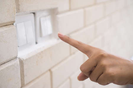 Female hand turning an electricity light switch on the wall