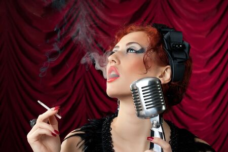 beautiful redhead woman smoking cigarette near vintage microphone