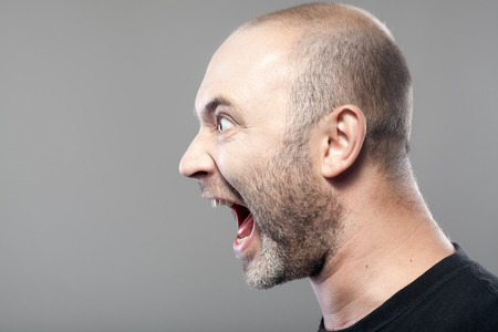 portrait of angry man screaming isolated on gray background with copyspaceの写真素材