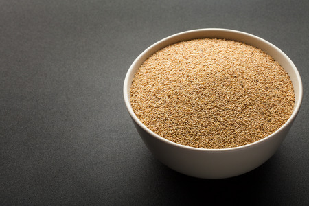 amaranth seeds in ceramic bowl isolated on dark backgroundの写真素材