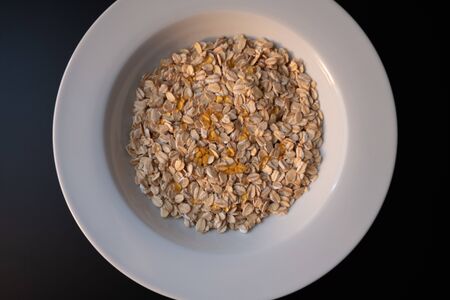 White plate with oat flakes and honey on a dark backgroundの写真素材