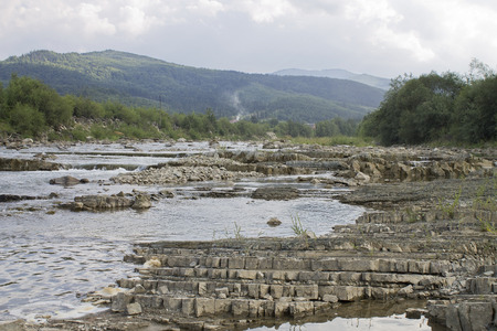 the mountain river flowing on stones with mountains on a backgroundの写真素材