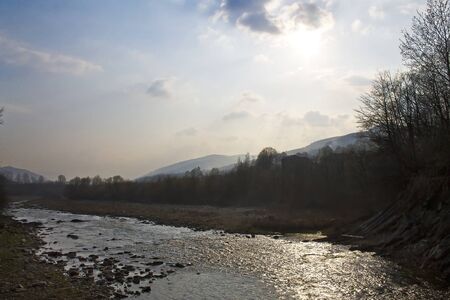 sunset on the mountain river flowing over rocksの写真素材