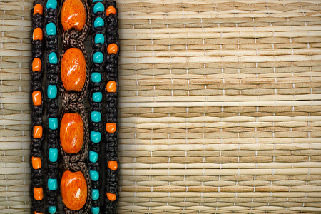 straw background with a border of woven bracelets with beadsの写真素材