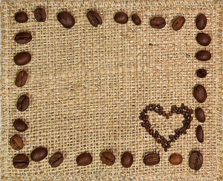 Frame of coffee beans with a heart on a burlap backgroundの写真素材