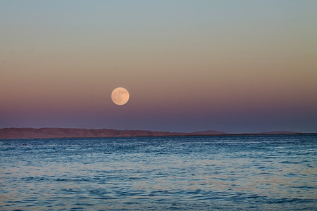 big full moon in the night sky over the seaの写真素材