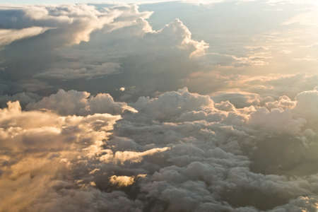 view from the airplane at the clouds, illuminated by the setting sunの写真素材