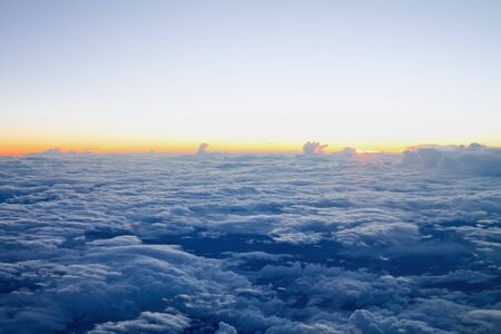 view from the airplane at the clouds, illuminated by the setting sunの写真素材