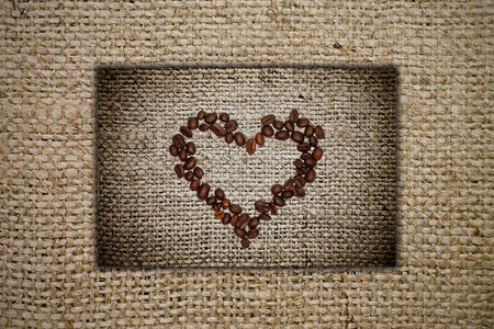 Heart of coffee beans on a burlap backgroundの写真素材
