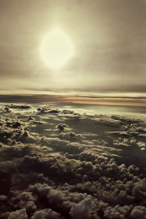 sun and clouds from an airplane window with a green tintの写真素材